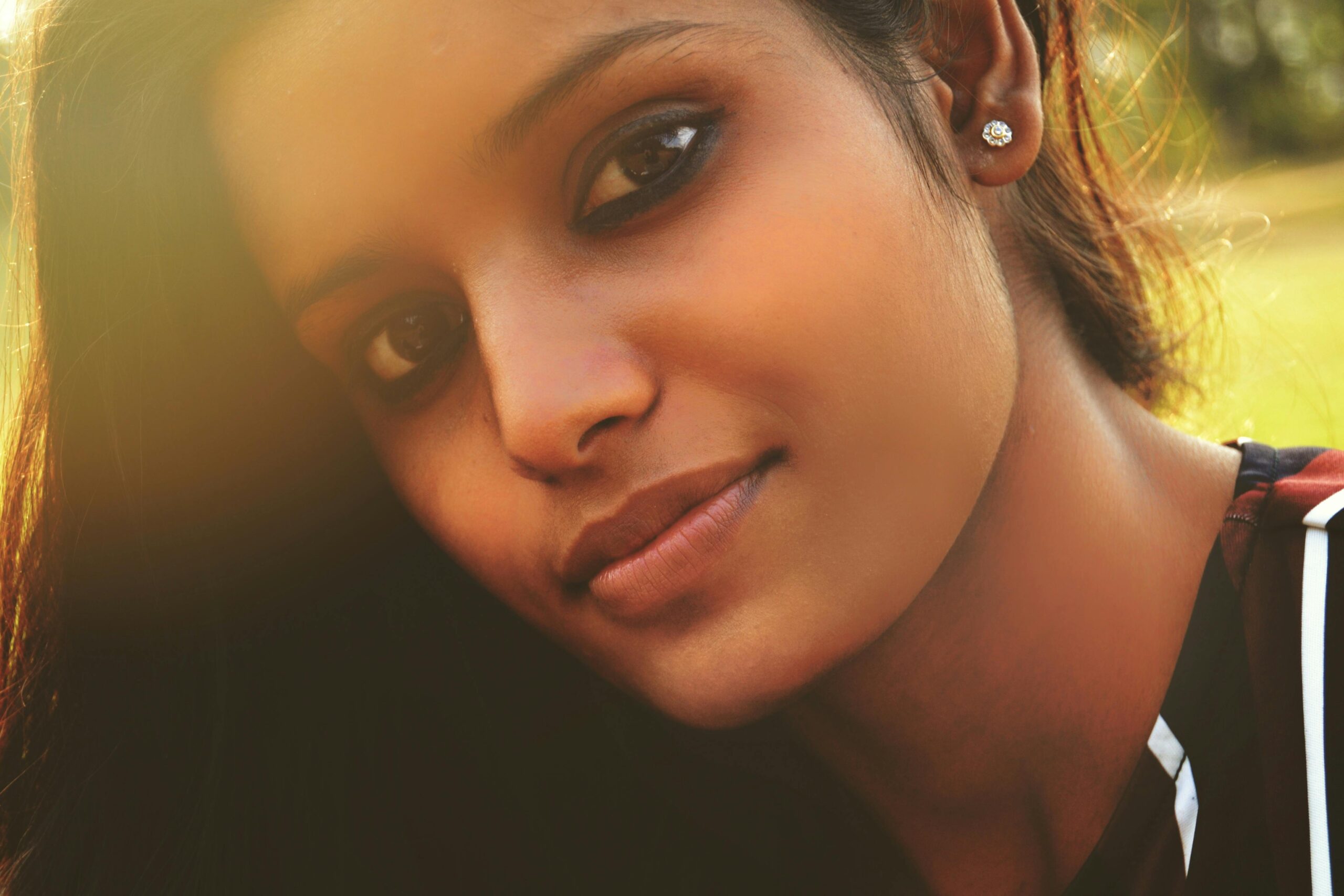 Close-up portrait of a young woman outdoors, with natural light creating a serene atmosphere.