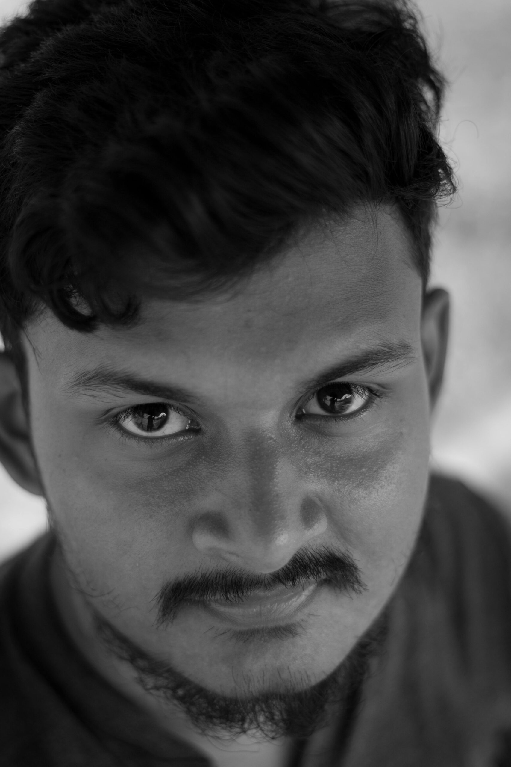 Close-up black and white portrait of a young adult male with expressive eyes.