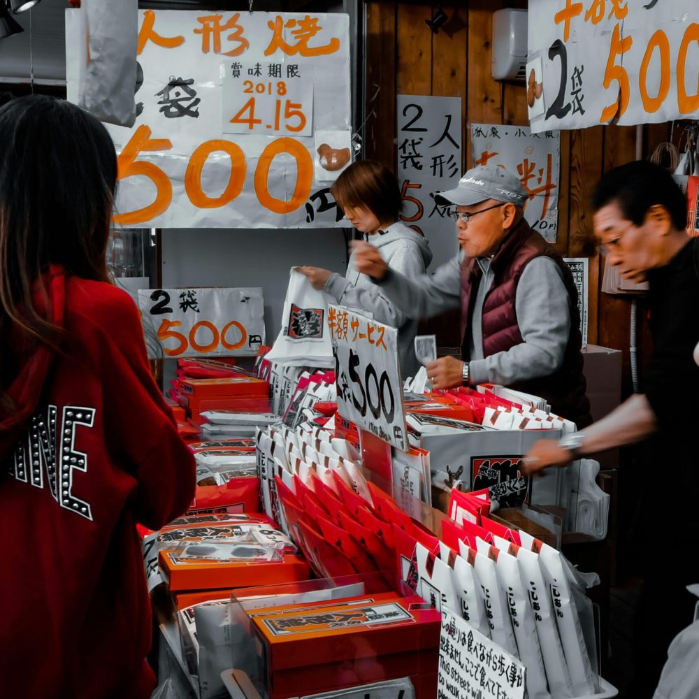 Busy street market with people buying and selling goods, vibrant atmosphere.