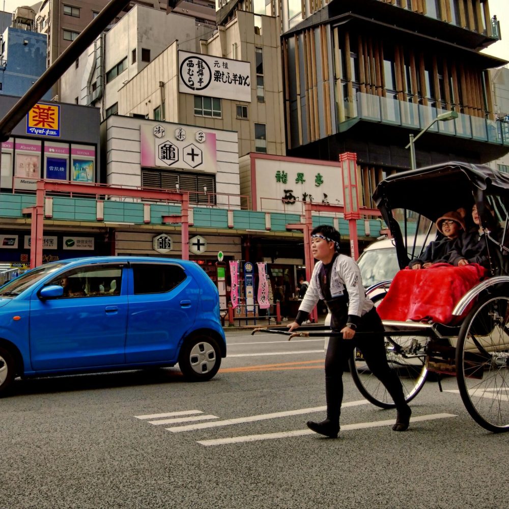 A rickshaw pulls tourists through Asakusa, Tokyo, blending tradition with modern city life.