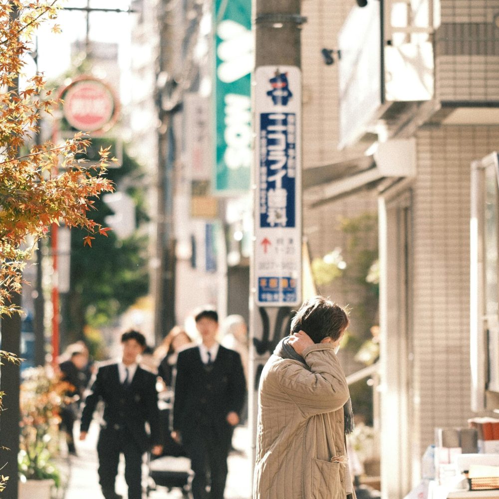 Bustling street in Japan featuring people, autumn leaves, and signage.