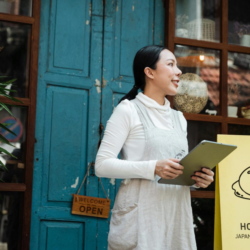 Woman with tablet standing outside a Japanese dessert cafe.