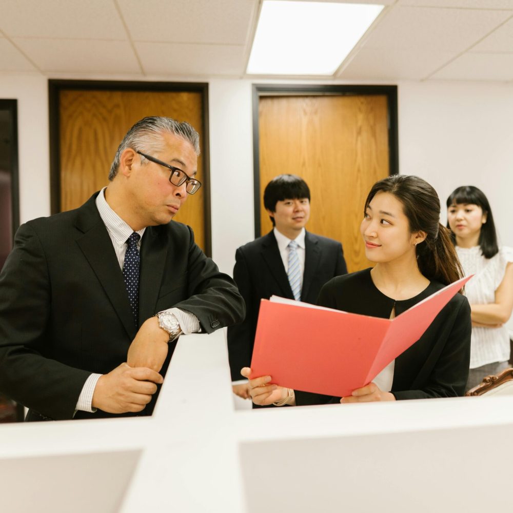 Business professionals discussing work documents in an office setting, showcasing teamwork.